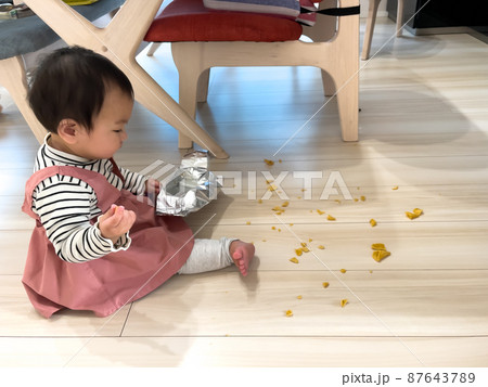 お菓子を散らかした1歳の女の子の赤ちゃん 87643789
