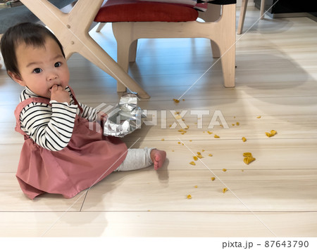 お菓子を散らかした1歳の女の子の赤ちゃん 87643790