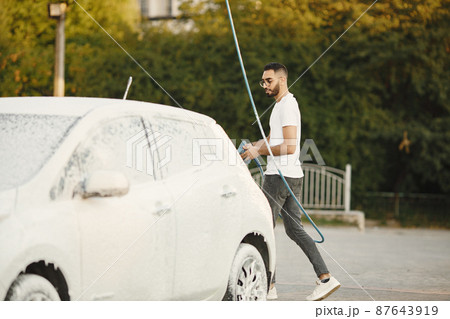 Indian man washing his white transportation on car wash Indian man washing his white transportation on car wash 87643919