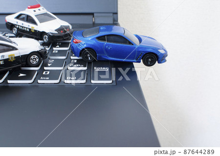 黒いキーボードと2台のパトカーと青いスポーツカー 87644289