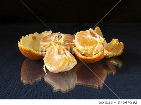Segments of the tangerine on glass table with reflection 87644592