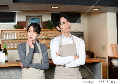 レストラン(飲食店)で悩むアジア人の男女の店員 レストラン(飲食店)で悩むアジア人の男女の店員 87645363