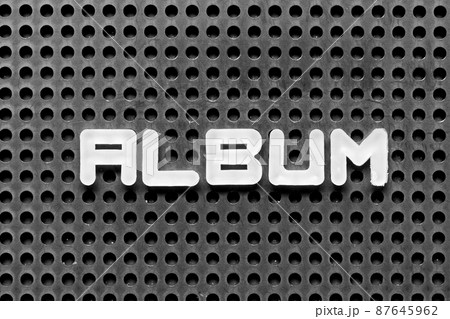 White alphabet letter in word album on black pegboard background 87645962