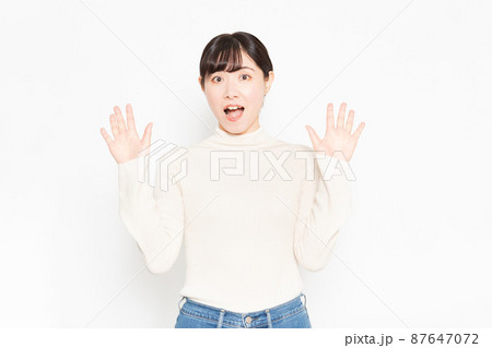 白い背景の前に立って驚いている女性 87647072