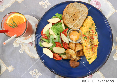 omelette , omelet or scrambled egg with salad and fried potato and strawberry smoothie 87648459