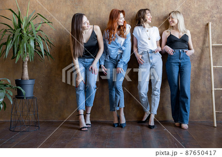 Portrait of four diverse girlfriends standing together on the wall background indoors 87650417