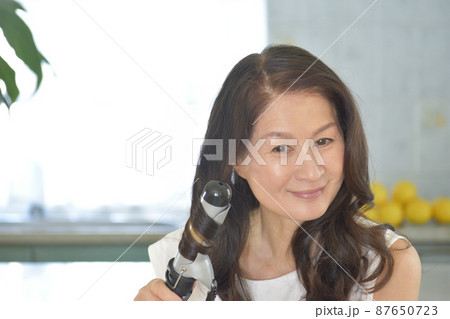ヘアアイロンで髪を巻く女性 ヘアアイロンで髪を巻く女性 87650723