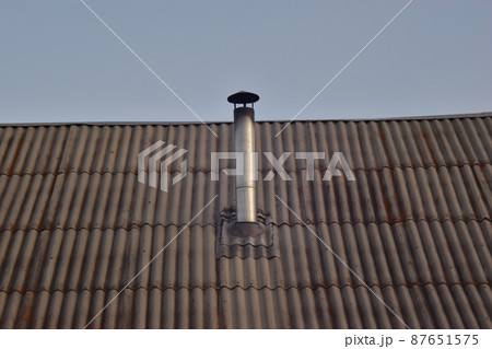 Chimney metal pipe home stove on the roof of the house 87651575