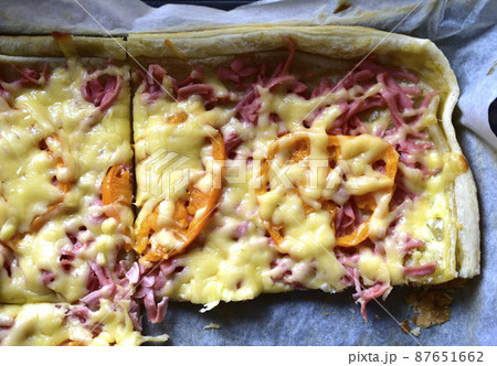 Homemade pizza with meat and yellow tomatoes on a baking sheet Homemade pizza with meat and yellow tomatoes on a baking sheet 87651662