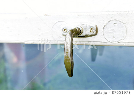 Old steel handle on the window pane of the old window 87651973