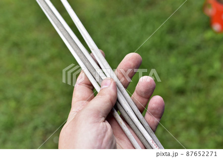 Welding electrodes in hands on a background of grass 87652271