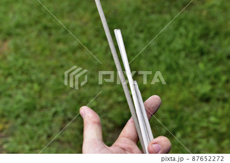 Welding electrodes in hands on a background of grass 87652272
