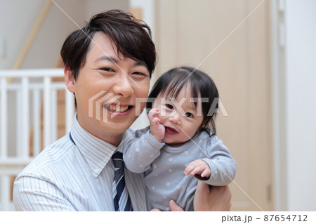 赤ちゃんを抱っこする会社員のパパ 87654712