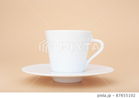 Close up of white ceramic coffee cup with saucer against pastel beige background with copy space Close up of white ceramic coffee cup with saucer against pastel beige background with copy space 87655102