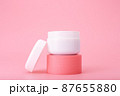 Opened cosmetic jar on pink pedestal against bright pink background. Concept of luxury repairing nourishing cream  87655880