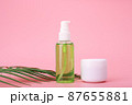 Green cleaning gel for face and cosmetic jar with cream or mask on pink background with palm leaf 87655881