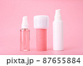 Set of beauty products in a row on white table against pink background. Face cleansing foam, cream and lotion 87655884