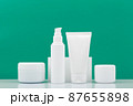 Set of cosmetic products for daily skincare in a row on white table against green background 87655898