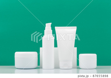 Set of cosmetic products for daily skincare in a row on white table against green background 87655898