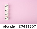 Four black checkmarks on white toy cubes in a row against bright pastel purple background with copy space 87655907