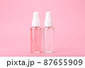 Two different face lotion, liquid foam or gel for skin cleaning in transparent tubes on bright pink background 87655909