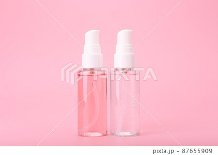 Two different face lotion, liquid foam or gel for skin cleaning in transparent tubes on bright pink background 87655909