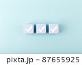 Three white checkmarks on blue toy cubes in a row on bright pastel blue background with copy space 87655925