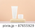 White cosmetic tubes with scrub and mask for face or hand skin on gypsum podium on white table against beige background.  87655929