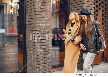 Two female friends in fashion clothes walking on the street Two female friends in fashion clothes walking on the street 87656627