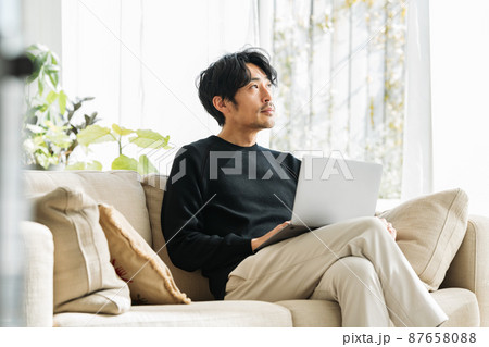 自宅のソファーでテレワークするミドル男性 自宅のソファーでテレワークするミドル男性 87658088