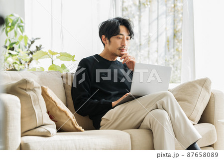 自宅のソファーでテレワークするミドル男性 87658089