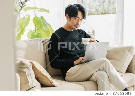 自宅のソファーでテレワークするミドル男性 自宅のソファーでテレワークするミドル男性 87658092