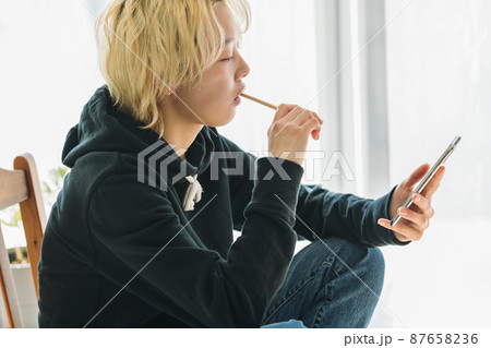 スマホを見ながら歯を磨く女性 87658236