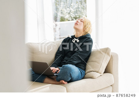 ソファーでパソコンを使うZ世代の女性 87658249