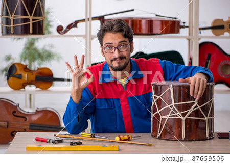 Young man repairing musical instruments at workshop 87659506