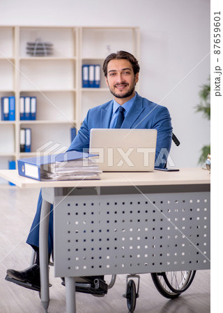 Young male employee in wheel-chair sitting in the office Young male employee in wheel-chair sitting in the office 87659601