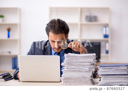 Young male employee and too much work in the office Young male employee and too much work in the office 87660327