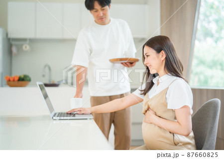 テレワークする妊婦と飲み物を持ってくる男性 87660825