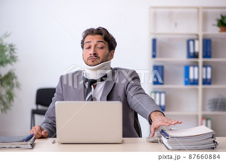 Young male employee after car accident working in the office Young male employee after car accident working in the office 87660884