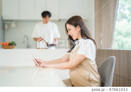 スマホを見る妊婦と家事をする男性 87661033