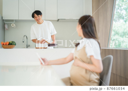 胎動を感じる妊婦と家事をする男性 87661034