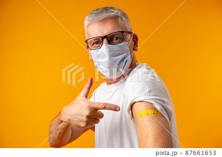 Senior man against yellow background recieved corona virus vaccination 87661653
