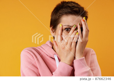 Portrait of the young scared teen woman against yellow background Portrait of the young scared teen woman against yellow background 87662346