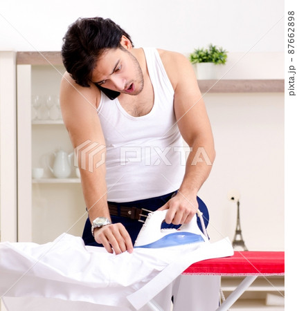 Young man ironing in the bedroom Young man ironing in the bedroom 87662898