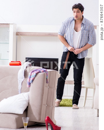 Man with mess at home after house party Man with mess at home after house party 87664307