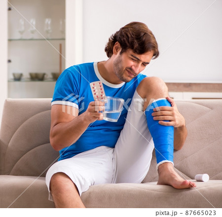 Leg injured young man on the sofa Leg injured young man on the sofa 87665023
