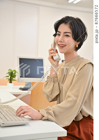オフィースで電話をする女性 87666572