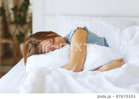 Portrait of young woman enjoying sleeping time in bed , close up ,elevated view, hugging pillow. Portrait of young woman enjoying sleeping time in bed , close up ,elevated view, hugging pillow. 87670303