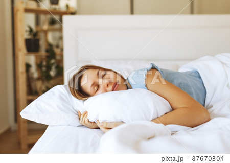 Portrait of young woman enjoying sleeping time in bed , close up ,elevated view, hugging pillow. Portrait of young woman enjoying sleeping time in bed , close up ,elevated view, hugging pillow. 87670304