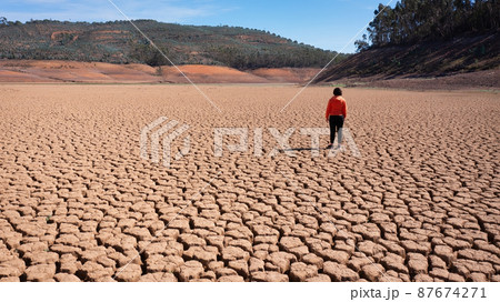 Silhouette of a man on a sandy cracked empty not fertile land during a drought. The concept of ecological catastrophe on the planet. 87674271
